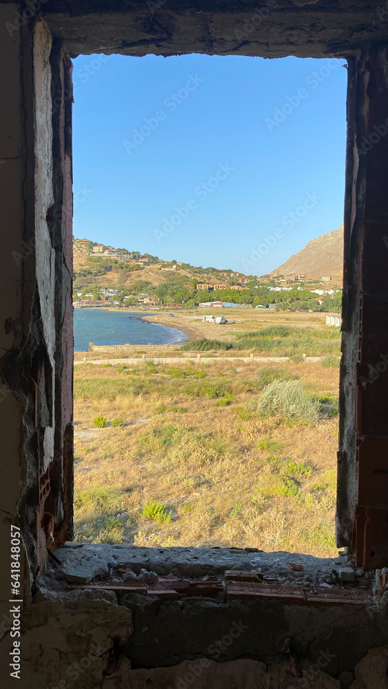 Window to the sea in an abandoned house across to Kalekoy sea town. The Aegean sea town view from window. Gokceada, Imbros island, Canakkale.