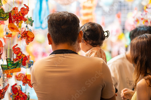 People in front of traditional colorful lanterns hanging on a stand in the streets of Cholon in Ho Chi Minh City, Vietnam during Mid Autumn Festival. Joyful and happy. photo