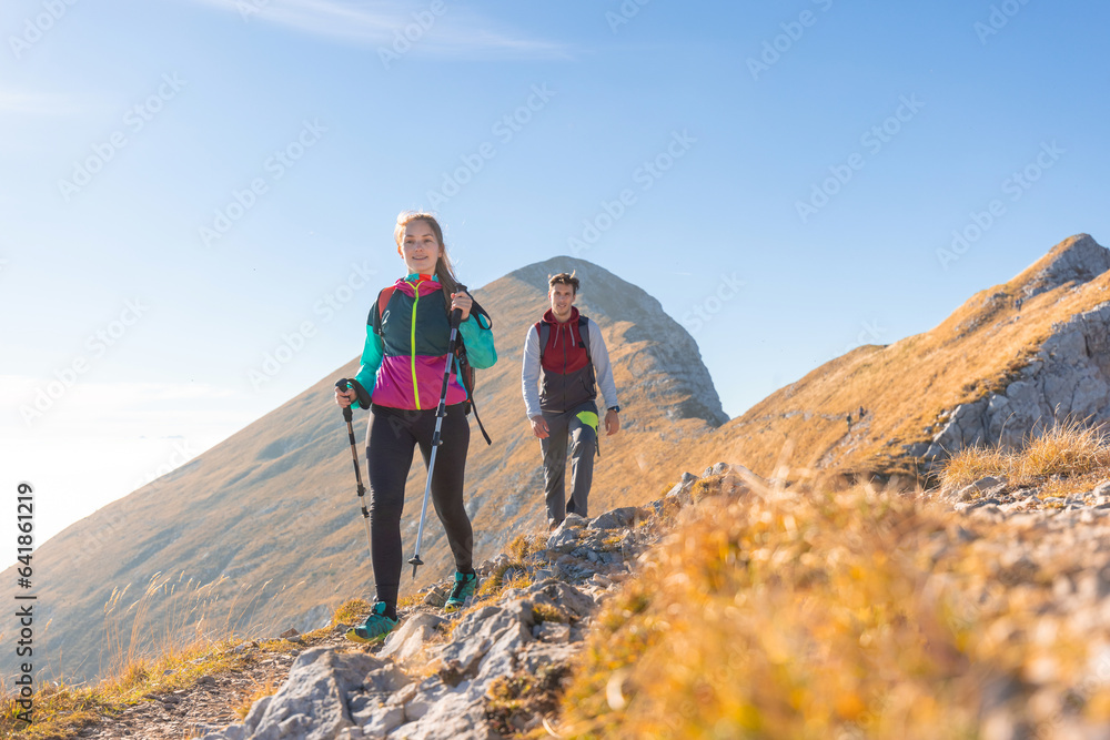 Hiking couple walking up mountain ridge on a sunny autumn day, aerial view. Life motivation, inspiration, effort, and tenacity concepts.