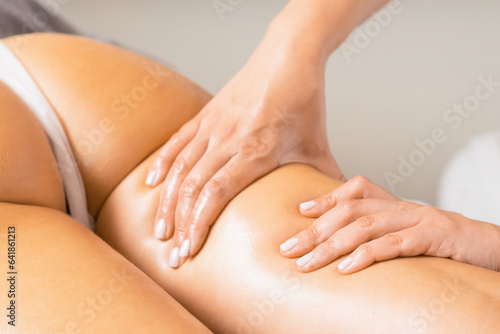 Beautician giving anti-cellulite hip massage to woman client in spa salon. Process of removing cellulite from woman thigh in beauty salon
