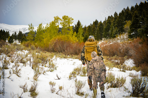 Father and son archery hunting for deer in the Montana snow