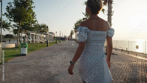 Sexy legs with high beige heels goes down the stairs of big city. Roamntic woman walking on boulvard alone. Attractive girl in short dress at summer season. Slow motion. High quality 4k footage photo