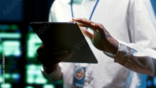 System administrator using tablet to check high tech facility security features protecting against unauthorized access  data breaches  phishing attacks and other cybersecurity threats  close up