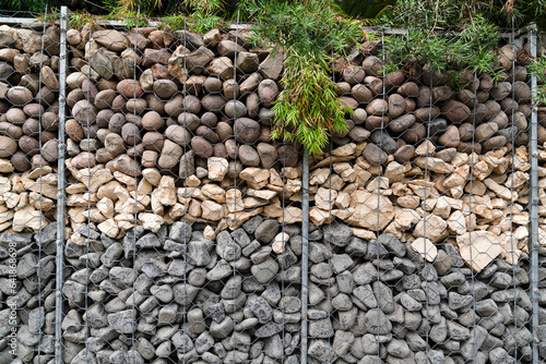 Gabion wall of metal mesh cage filled with different colors rocks in National Botanic Garden of Belgium in Meise photo