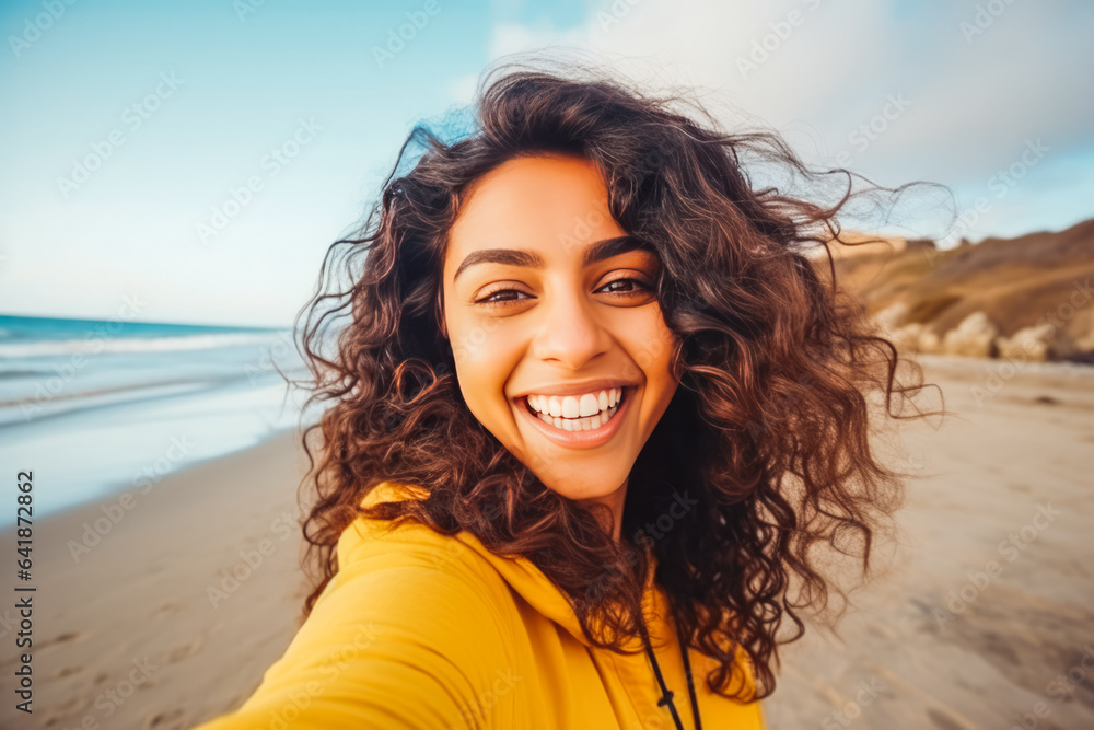 Beautiful young indian woman enjoying a day on the beach while smiling and making a picture