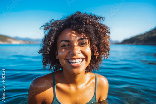 Portrait of beautiful young african american woman smiling and having fun while swimming in ocean