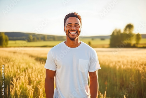 Portrait of handsome young african american man smiling while standing in field of wheat, natural light