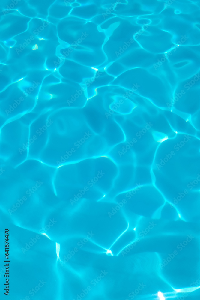 Azure transparent texture of water in a blue pool with splashes from the sun