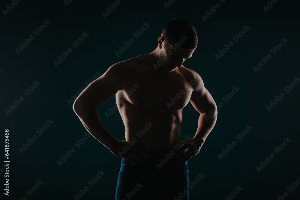 Fototapeta premium Fit male sports person posing in studio. He is looking at his abs.