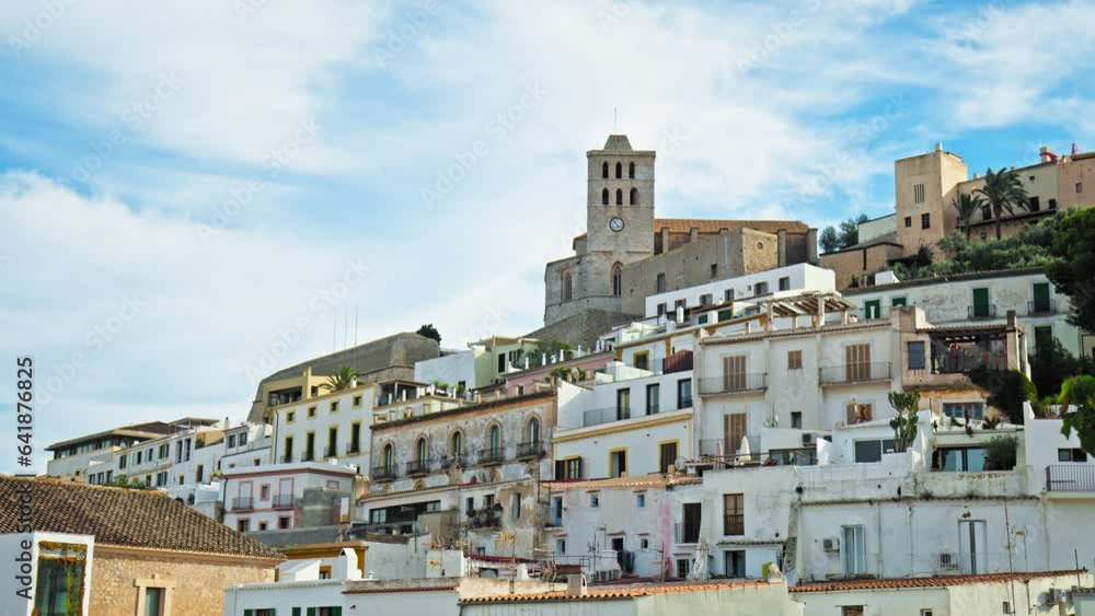 Beautiful view of Eivissa old town and its fortress with iconic tower clock. Old architecture and buildings of the Ibiza Town capital city on a sunny day with blue sky on the Balearic Islands, Spain Beautiful view of Eivissa old town and its fortress with iconic tower clock. Old architecture and buildings of the Ibiza Town capital city on a sunny day with blue sky on the Balearic Islands, Spain