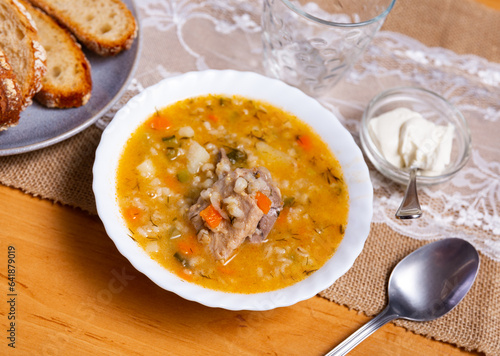 Soup with pickled cucumbers and pearl barley - rassolnik on wooden background. © JackF