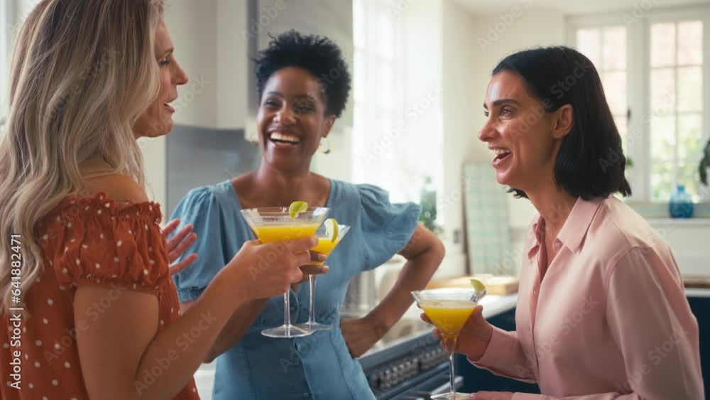 Three mature female friends at home having fun in kitchen drinking cocktails together - shot in slow motion Three mature female friends at home having fun in kitchen drinking cocktails together - shot in slow motion