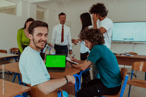 A group of business colleagues exchange knowledge and insights while utilizing laptops in the office, showcasing collaborative learning, effective communication, and a dynamic corporate environment