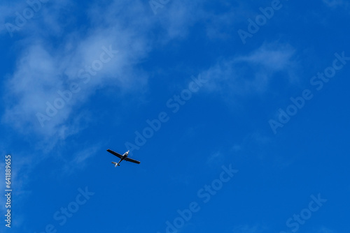 Small white cessna single propeller plane flying in a clear blue sky . High quality photo