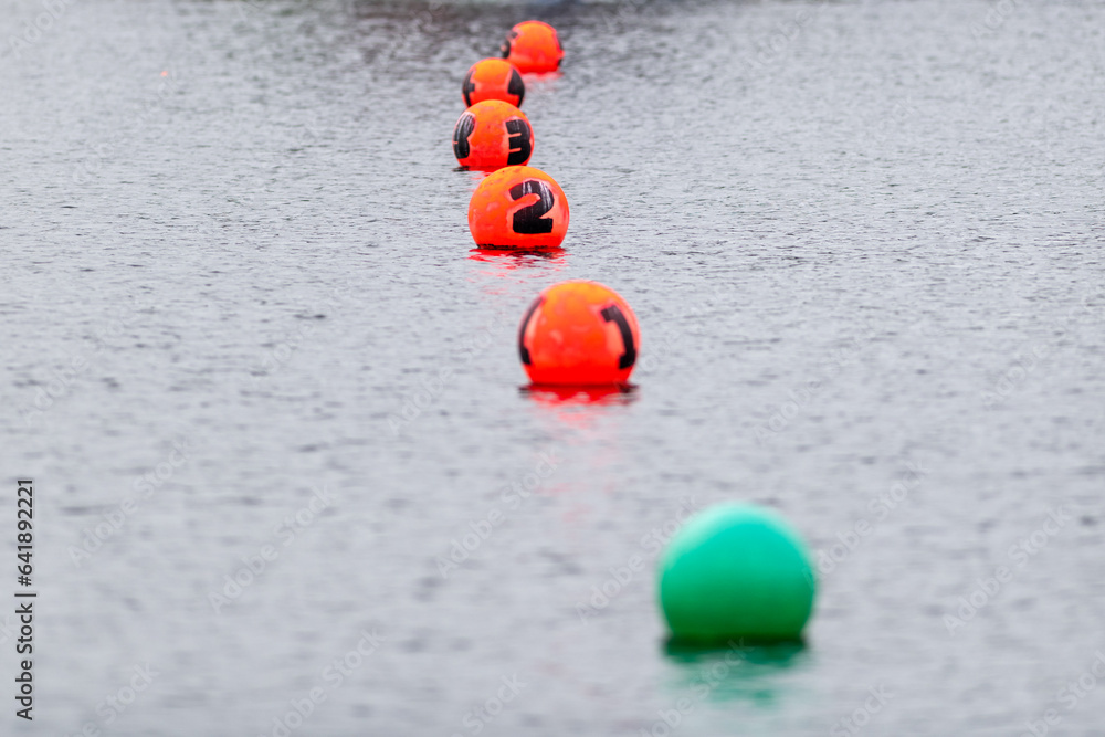 A row of orange colored buoys at the finish line of a boating race. The