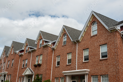 Fototapete A row of brown brick townhouses with peaked gable roofs, and double hung windows with white trim