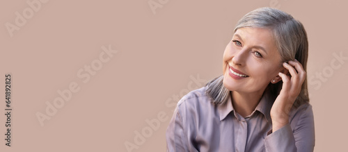 Portrait of beautiful mature woman on beige background. Banner design with space for text