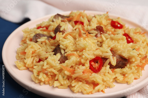 Delicious pilaf with meat on blue table, closeup