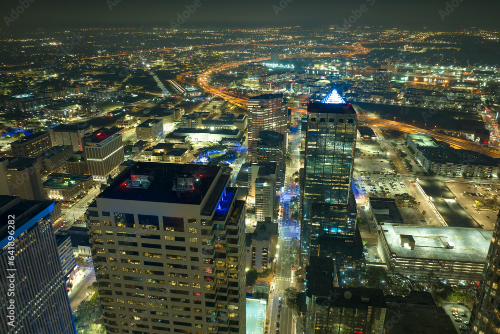 View from above of brightly illuminated high skyscraper buildings in downtown district of Tampa city in Florida, USA. American megapolis with business financial district at night