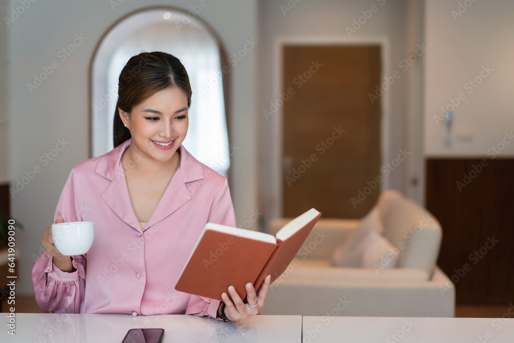 Female entrepreneur drinking coffee and reading a book with happiness to relaxation in home office Female entrepreneur drinking coffee and reading a book with happiness to relaxation in home office