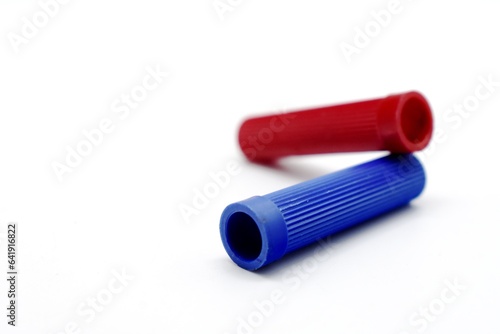 The two red and blue marker caps made of plastic appear photographed on the isolated white background