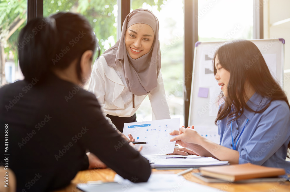 Fototapeta premium A confident Asian Muslim businesswoman is listening her teams ideas in the meeting.