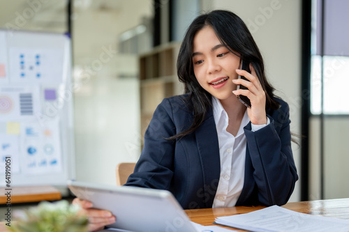 A professional businesswoman is making a call to her client to discuss a contract over the phone