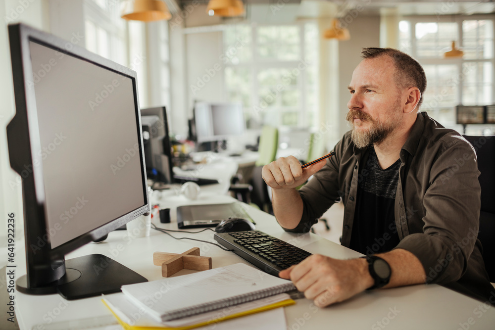 Middle aged caucasian man using a computer at a office job Middle aged caucasian man using a computer at a office job