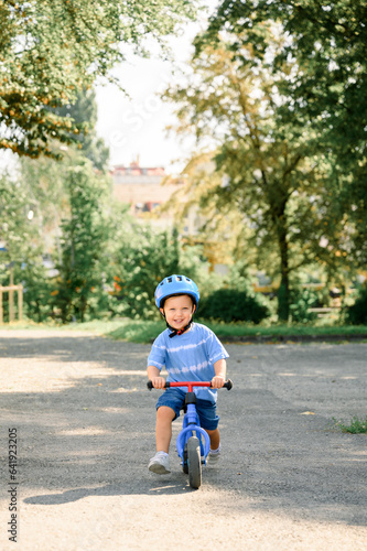 Happy child riding balance bike. Male toddler kid in helmet learning to ride on run bicycle © Franci Leoncio