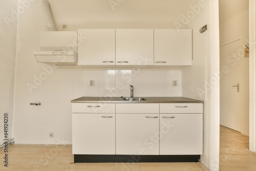 a kitchen with white cupboards and black counter tops on the floor in a small room that has wood floors