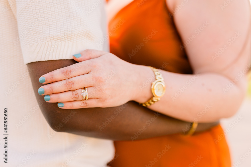 A Caucasian woman who is engaged has her hands on her Black fiance's arm. 