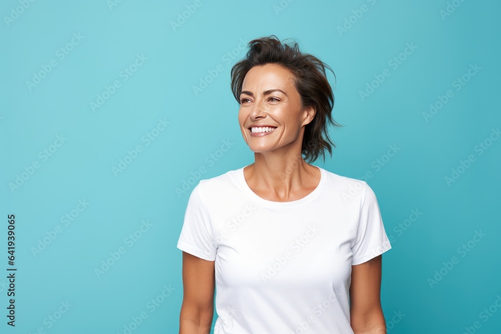 Close up of a 40s middle age woman smiling and wearing a white t-shirt on a turquoise background. Healthy face skin care beauty, skincare cosmetics, dental. Close up of a 40s middle age woman smiling and wearing a white t-shirt on a turquoise background. Healthy face skin care beauty, skincare cosmetics, dental.
