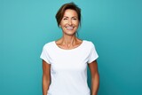 Close up of a 40s middle age woman smiling and wearing a white t-shirt on a turquoise background. Healthy face skin care beauty, skincare cosmetics, dental.