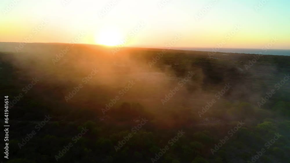 Misty haze fog smoke rises spread across shrub landscape at golden hour orange glow in air Misty haze fog smoke rises spread across shrub landscape at golden hour orange glow in air