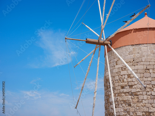 Windmills in the Mandraki port of Rhodes, Greece. Old defensive stands and windmills. Wharf harbors, boats and sailing ships. Historic pier and beach. Travel to Mediterranean islands Rhodes.