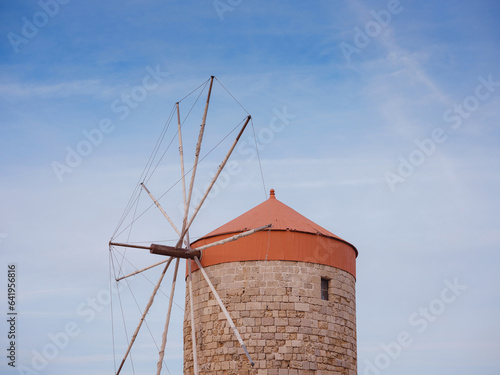 Windmills in the Mandraki port of Rhodes, Greece. Old defensive stands and windmills. Wharf harbors, boats and sailing ships. Historic pier and beach. Travel to Mediterranean islands Rhodes.