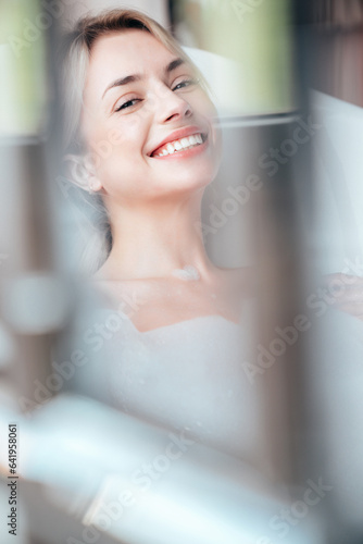 Free Download Portrait of young beautiful sexy woman having fun while lying in bathtub full of foam at home. Charming smiling model relaxing in luxury bath interior. Female enjoying beauty and skincare day - GFXLoad