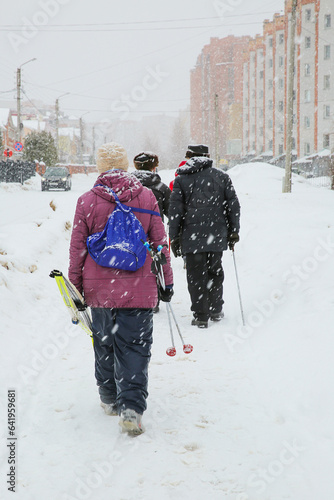 People walk down the street in a snowfall in the city