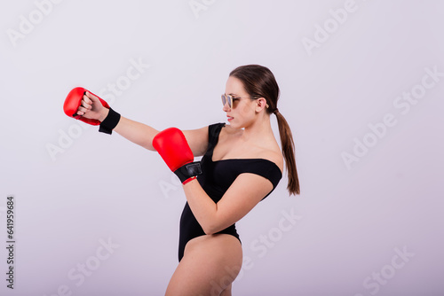 Seductive female boxer with athletic beautiful figure in black swimsuit gloves on gray background photo