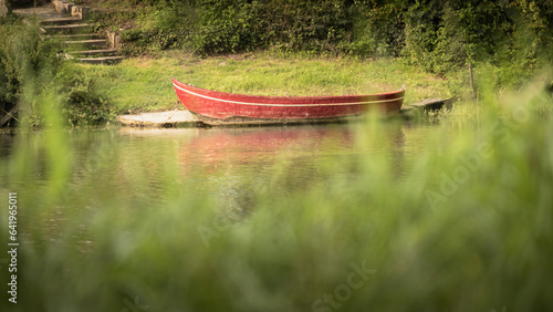 Bateau rouge sur le lac avec de l'herbe verte en arrière-plan. Mise au point sélective.