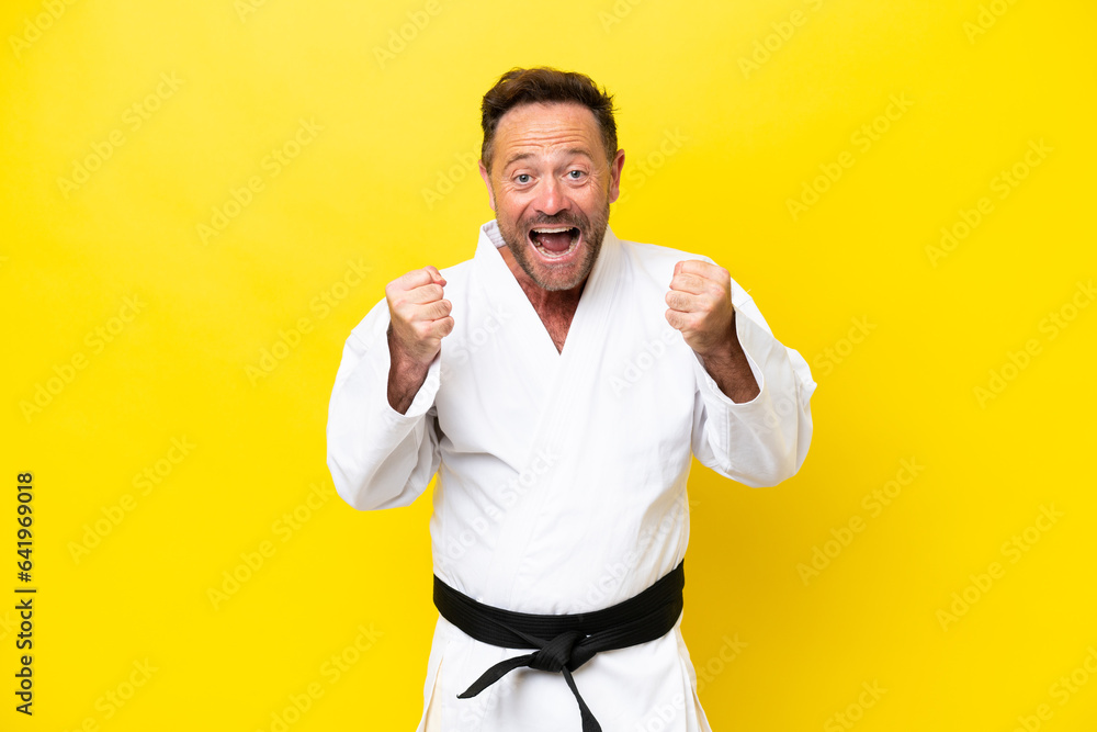 Middle age caucasian man doing karate isolated on yellow background celebrating a victory in winner position Middle age caucasian man doing karate isolated on yellow background celebrating a victory in winner position