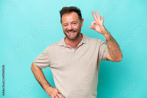 Middle age caucasian man isolated on blue background showing ok sign with fingers
