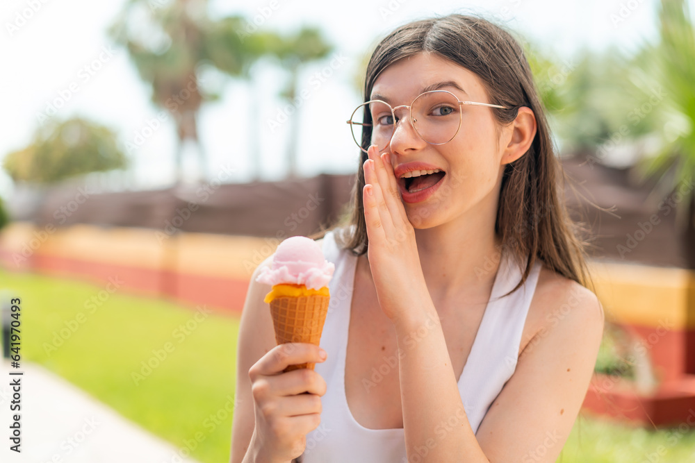 Young pretty Ukrainian woman with a cornet ice cream at outdoors whispering something Young pretty Ukrainian woman with a cornet ice cream at outdoors whispering something