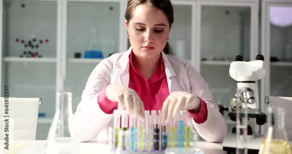 Laboratory practitioner replaces tubes of liquids in modern premise. Woman specialist in robe prepares for lab examination concept slow motion Laboratory practitioner replaces tubes of liquids in modern premise. Woman specialist in robe prepares for lab examination concept slow motion
