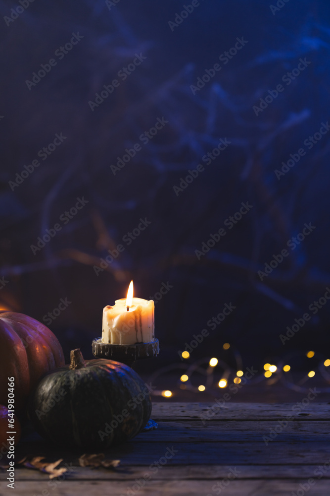 Fototapeta premium Vertical image of pumpkins and candle with copy space on dark background