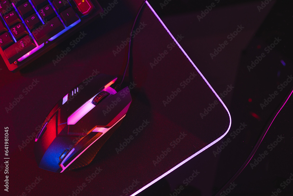 Composite of computer keyboard with video game accessories with copy space on neon background