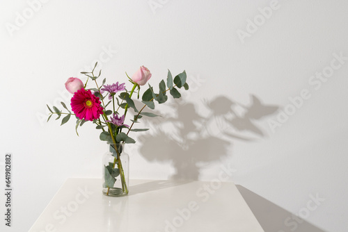 Pink flowers in glass vase and copy space on white background