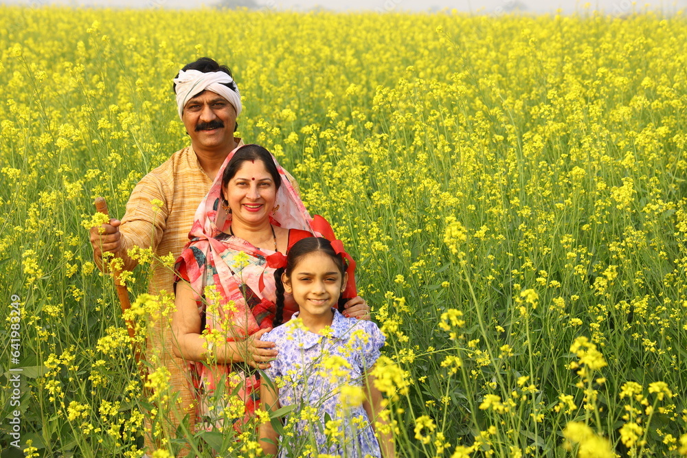 Happy rural Indian family standing in a mustard field and enjoying the benefits of the agricultural field. Happy rural Indian family standing in a mustard field and enjoying the benefits of the agricultural field.