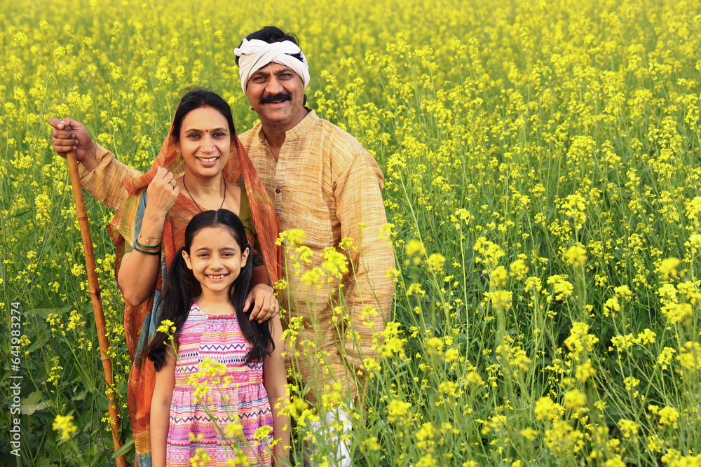 Happy rural Indian family standing in a mustard field and enjoying the benefits of the agricultural field. Happy rural Indian family standing in a mustard field and enjoying the benefits of the agricultural field.