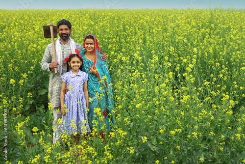 Happy rural Indian family standing in a mustard field and enjoying the benefits of the agricultural field.